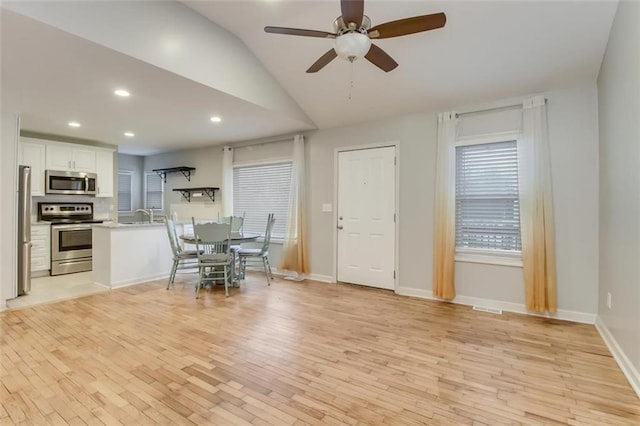 dining area featuring sink, vaulted ceiling, ceiling fan, and light wood-type flooring