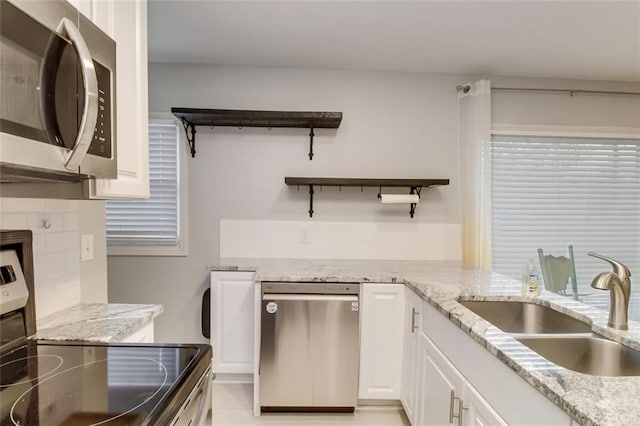 kitchen featuring sink, white cabinetry, tasteful backsplash, light stone counters, and appliances with stainless steel finishes