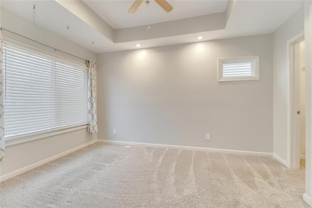 carpeted spare room with a tray ceiling and ceiling fan