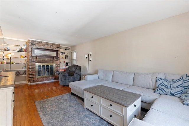 living room with wood-type flooring and a brick fireplace