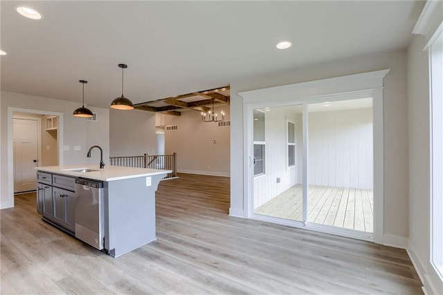 kitchen with pendant lighting, dishwasher, beamed ceiling, sink, and a kitchen island with sink