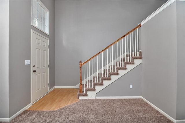 foyer entrance with carpet floors, stairway, a towering ceiling, and baseboards