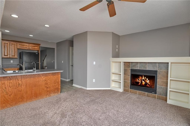 kitchen featuring brown cabinets, open floor plan, freestanding refrigerator, a fireplace, and dark carpet