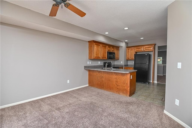 kitchen with brown cabinets, light carpet, a sink, a peninsula, and black appliances