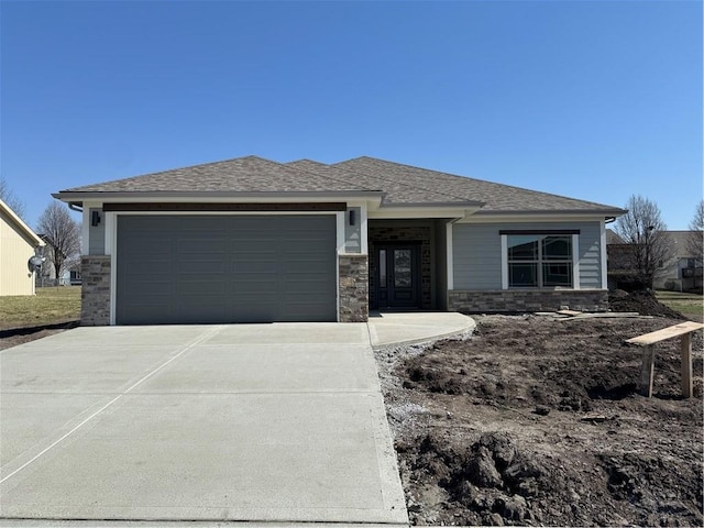 view of front facade featuring an attached garage, driveway, and roof with shingles