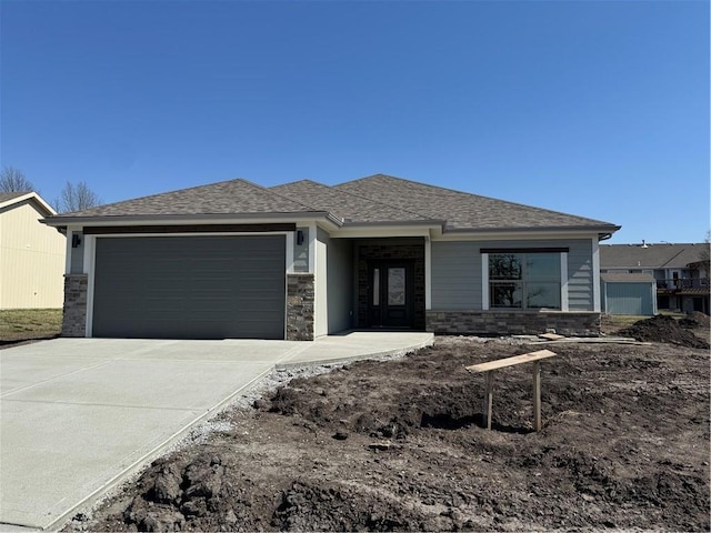 prairie-style home featuring an attached garage, driveway, and roof with shingles