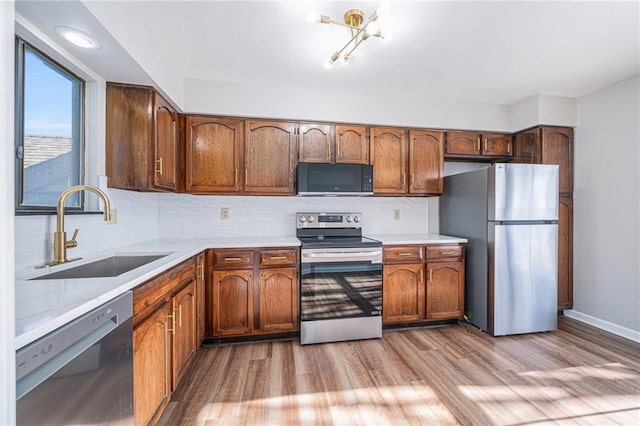 kitchen featuring sink, black appliances, light hardwood / wood-style flooring, and tasteful backsplash