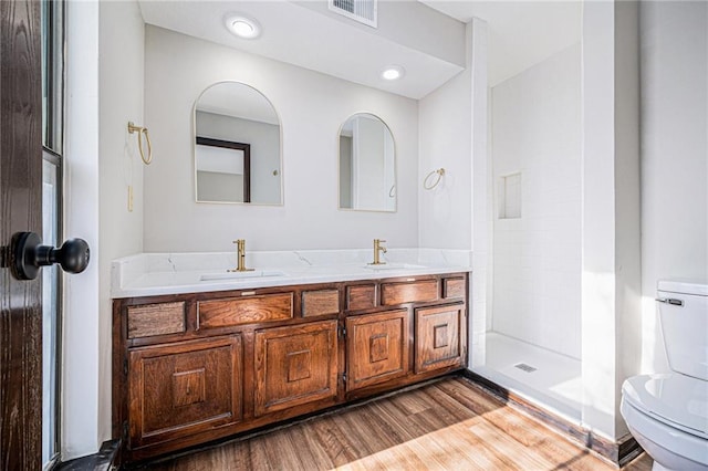 bathroom featuring hardwood / wood-style flooring, a shower, toilet, and vanity