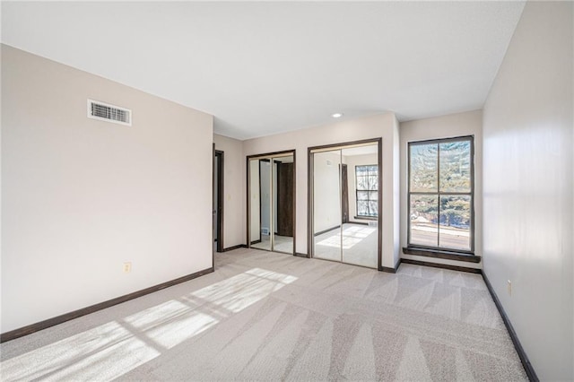 unfurnished bedroom with multiple closets and light colored carpet