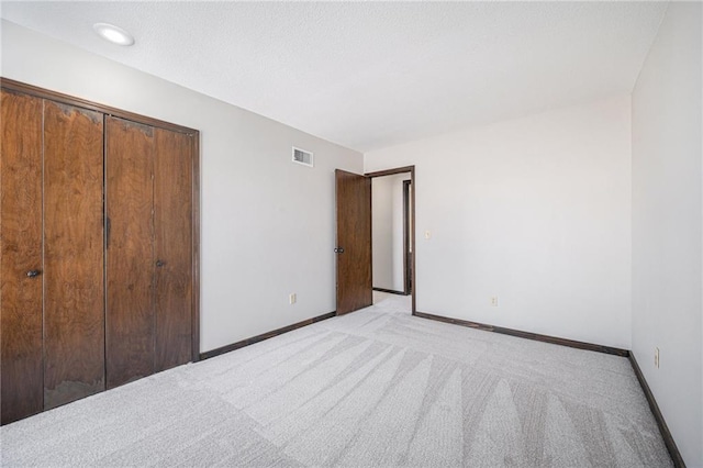 unfurnished bedroom with a closet and light carpet