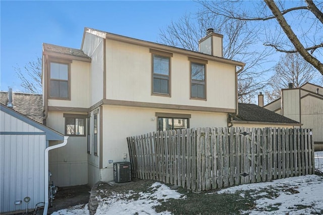 snow covered back of property with central AC