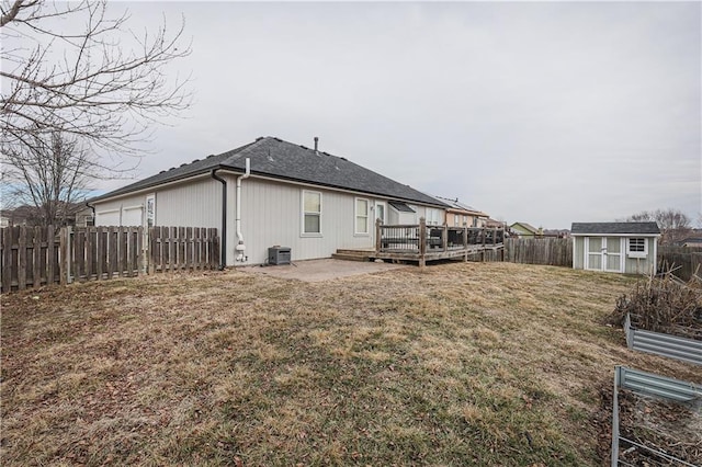 back of house featuring a deck, central AC unit, a lawn, and a storage shed