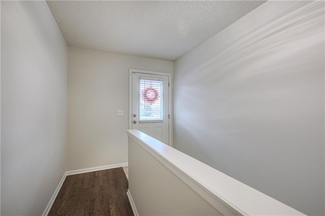 corridor featuring a textured ceiling and dark hardwood / wood-style flooring