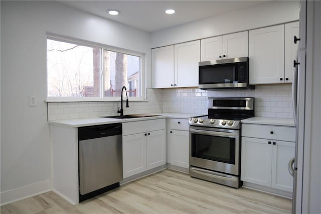 kitchen with white cabinetry, appliances with stainless steel finishes, light hardwood / wood-style floors, and sink