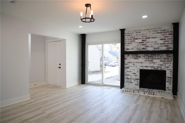 unfurnished living room featuring a fireplace, light hardwood / wood-style flooring, and a notable chandelier