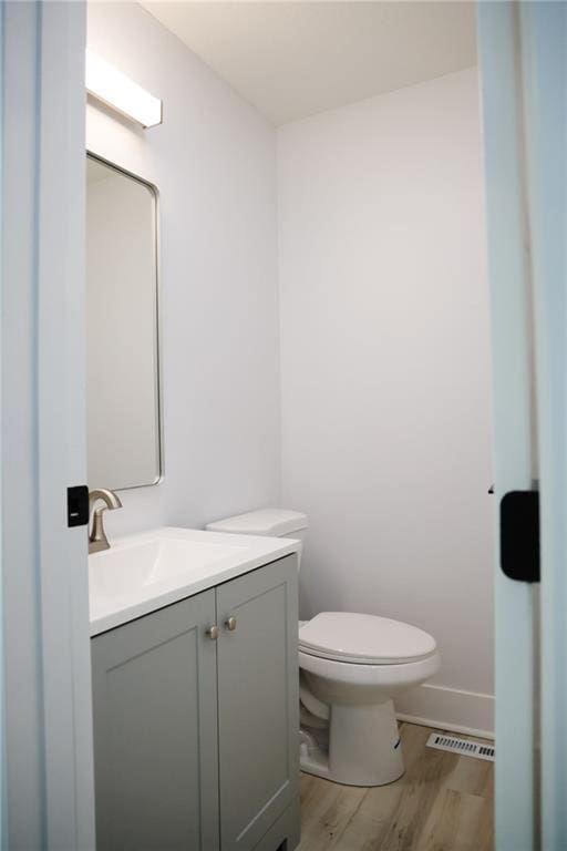 bathroom with wood-type flooring, toilet, and vanity