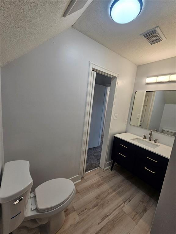 bathroom featuring vanity, hardwood / wood-style flooring, toilet, and a textured ceiling