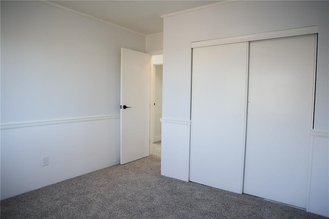 unfurnished bedroom featuring crown molding, carpet floors, and a closet