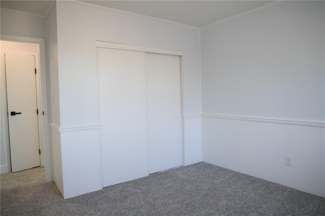 unfurnished bedroom featuring crown molding, carpet floors, and a closet