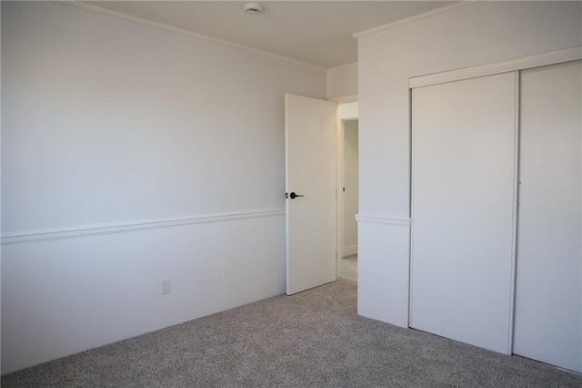 unfurnished bedroom featuring a closet, ornamental molding, and carpet