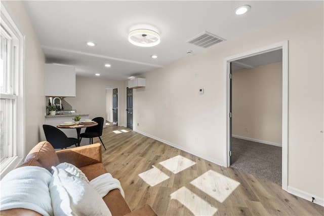 living room featuring a wall mounted AC and light hardwood / wood-style flooring