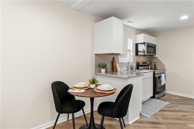 kitchen featuring stainless steel appliances, white cabinetry, tasteful backsplash, and sink