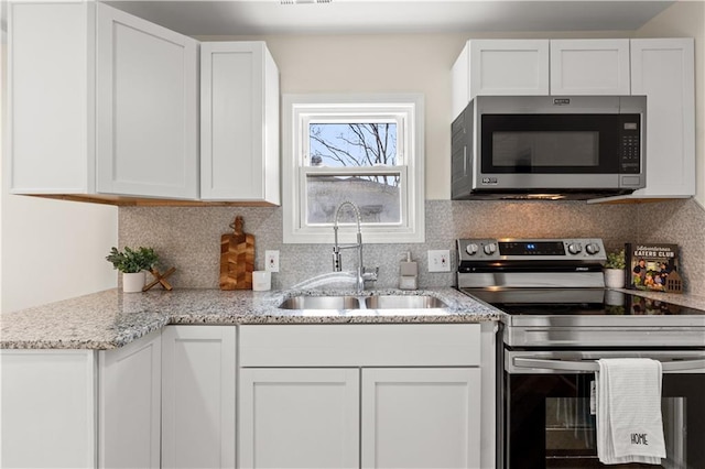 kitchen with backsplash, appliances with stainless steel finishes, sink, and white cabinets