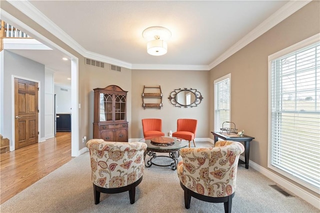 sitting room with ornamental molding and light colored carpet