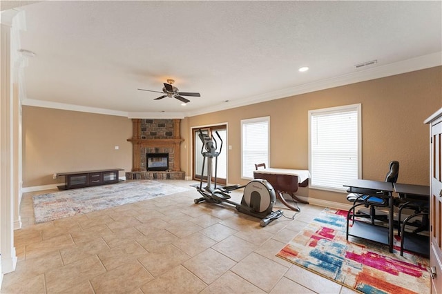 workout area featuring ornamental molding, a large fireplace, light tile patterned flooring, and ceiling fan