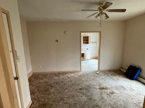 carpeted spare room with ceiling fan and a baseboard heating unit