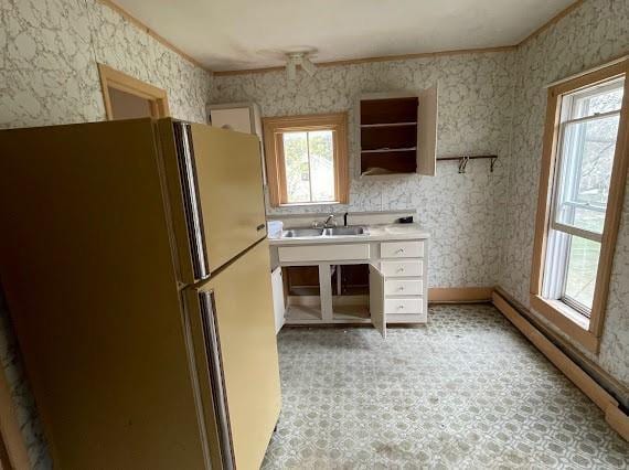 kitchen featuring fridge, sink, baseboard heating, and crown molding