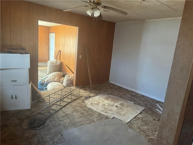 carpeted bedroom featuring wooden walls and ceiling fan