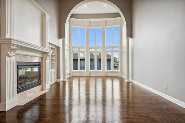 4749 SW Gull Point Dr, Lees Summit, MO 64082 - unfurnished living room featuring wood finished floors, a fireplace, a high ceiling, recessed lighting, and arched walkways