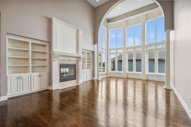 4749 SW Gull Point Dr, Lees Summit, MO 64082 - unfurnished living room featuring dark wood-style floors, a high end fireplace, a high ceiling, and built in shelves