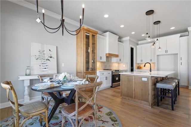 kitchen with premium range hood, stainless steel electric stove, white cabinets, backsplash, and an island with sink