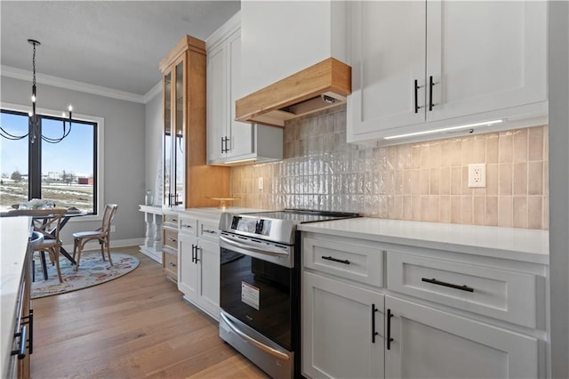 kitchen featuring stainless steel electric stove, white cabinetry, a notable chandelier, ornamental molding, and light hardwood / wood-style floors