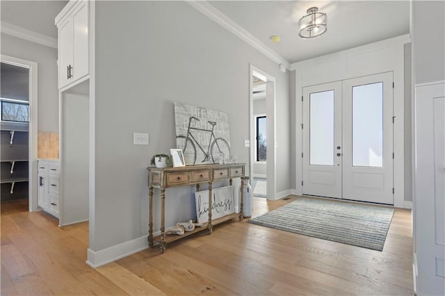 foyer entrance featuring light hardwood / wood-style floors, crown molding, french doors, and a healthy amount of sunlight