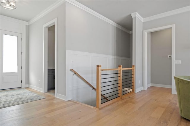 foyer entrance with ornamental molding, a chandelier, and light wood-type flooring