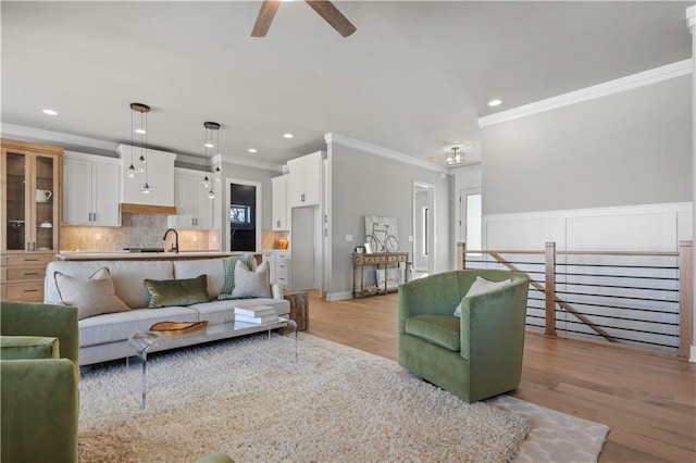 living room with sink, ceiling fan, light hardwood / wood-style flooring, and ornamental molding