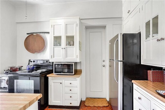 kitchen featuring electric range, stainless steel fridge, and white cabinets