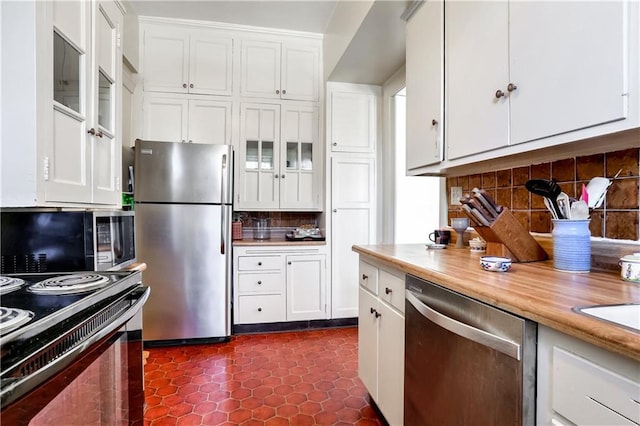 kitchen featuring stainless steel appliances, white cabinets, wood counters, and decorative backsplash