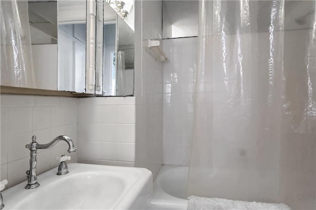 bathroom with shower / tub combo with curtain, sink, tasteful backsplash, and tile walls