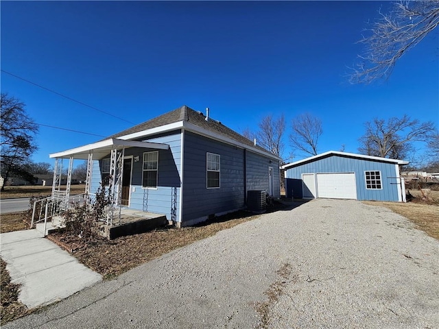 view of side of home featuring an outbuilding, cooling unit, a garage, and covered porch