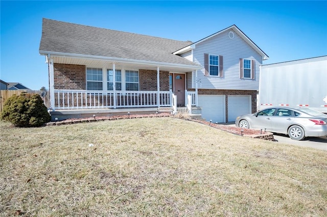 split level home with a garage, covered porch, a front lawn, and brick siding