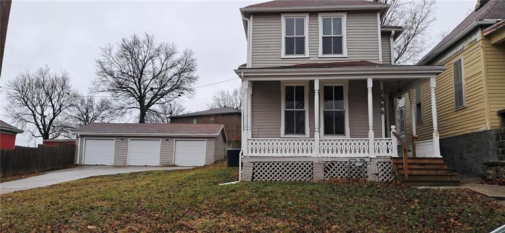 view of front of home with a porch, a garage, an outbuilding, and a front yard