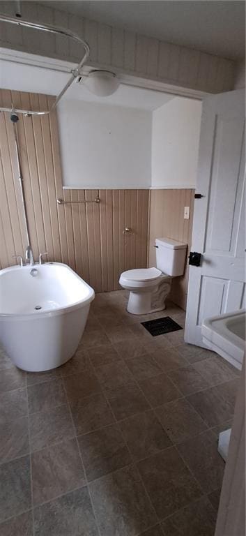 bathroom featuring toilet and wooden walls