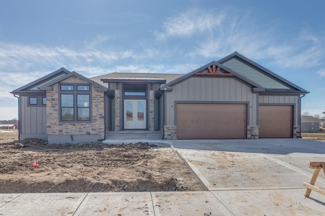 view of front of home featuring stone siding, french doors, board and batten siding, and driveway