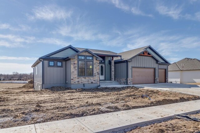 view of front of home with an attached garage, stone siding, board and batten siding, and concrete driveway