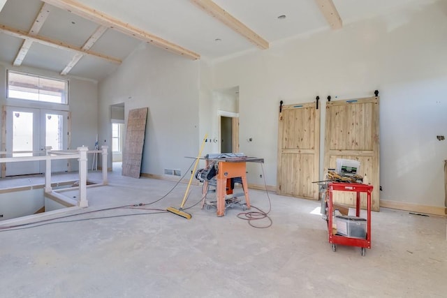 miscellaneous room with beam ceiling, unfinished concrete flooring, a towering ceiling, and visible vents