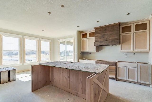 kitchen featuring light stone countertops, a kitchen island, and unfinished concrete floors